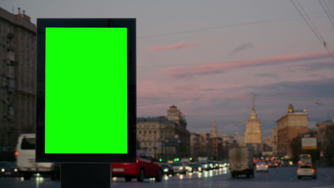 Green screen blank billboard on a busy street at sunset