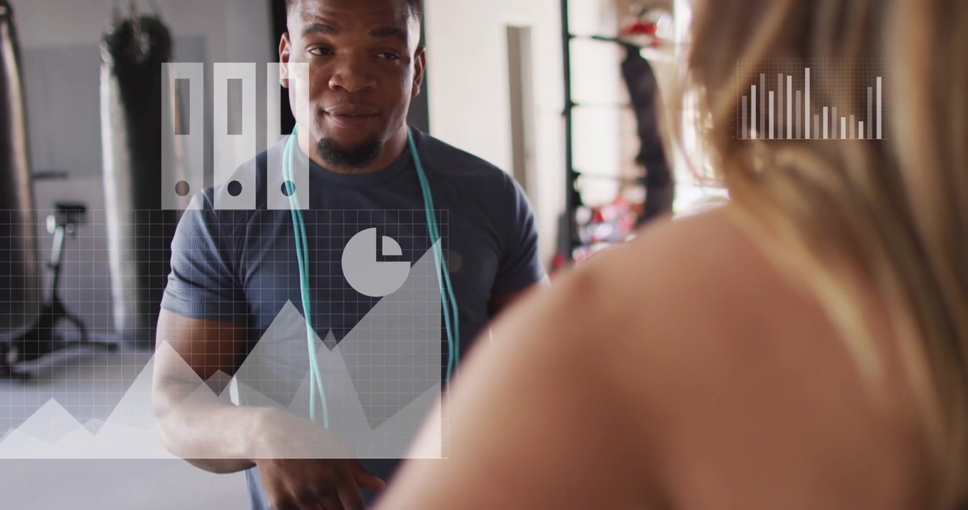 Vertical video: Pointing trainer in dark tee coaching client in gym, with teal jump rope and charts