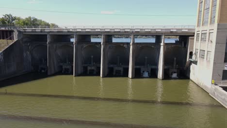 Water-slowly-streaming-through-Ypsilanti-water-dam,-aerial-low-altitude-view