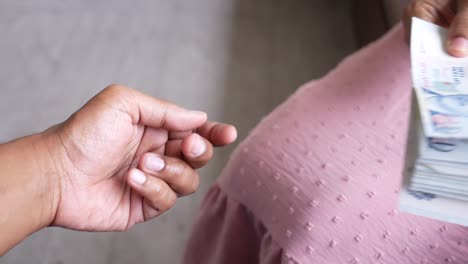 hombre que nos da dinero en efectivo en dólares a una mujer