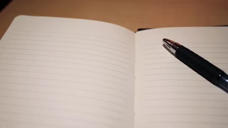 slow motion high angle tracking shot of pen and journal open to empty page