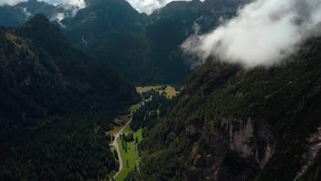 Dolomite-park-in-northern-Italy-with-a-grassy-canyon-gorge-below-on-a-clear-winter-day,-Aerial-drone-pan-left-reveal-shot