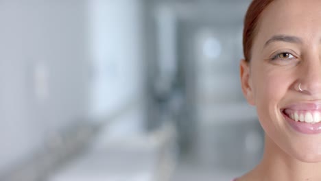 Portrait-of-happy-biracial-female-doctor-smiling-in-corridor,-copy-space,-slow-motion