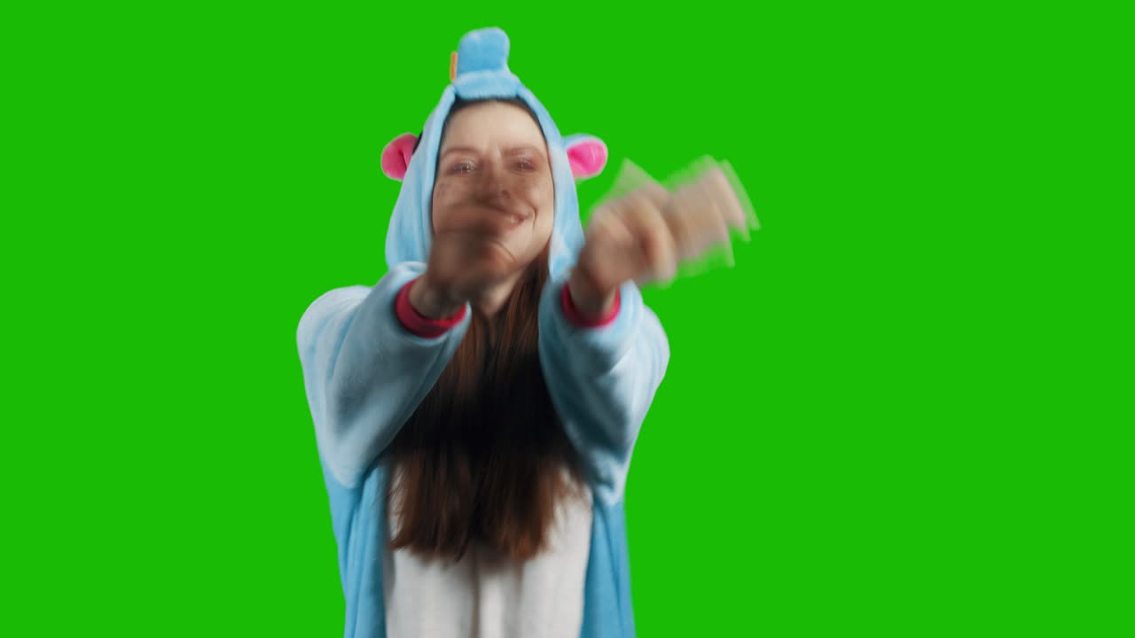 Portrait of a cute young brunette girl in a beautiful unicorn costume on chrome key green background. Smiling and playing. Animator in costume. Unicorn pajamas. 4K video with alpha channel