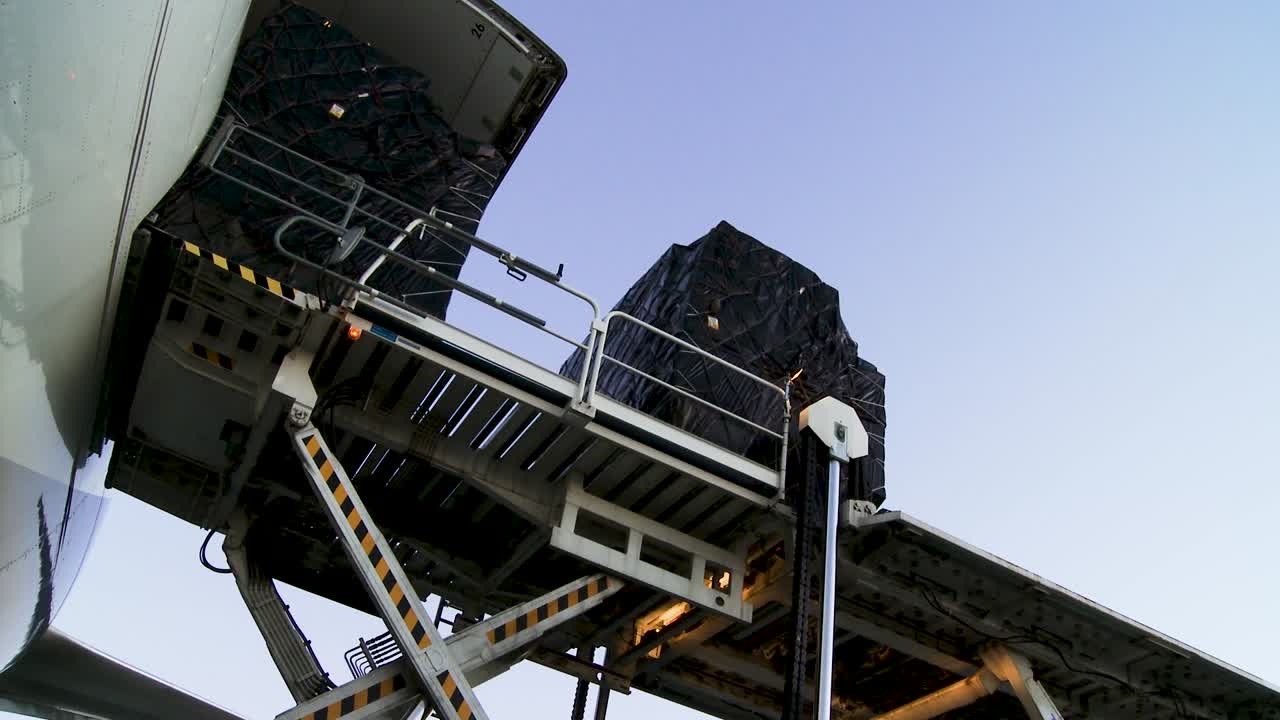 Cargo being loaded onto an airplane at sunset, showcasing aviation logistics