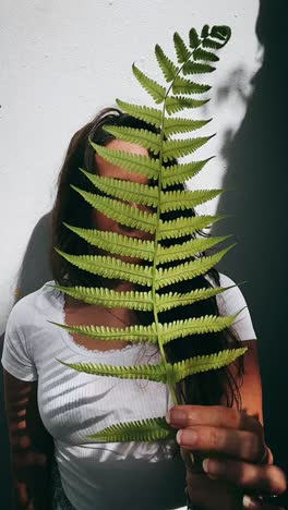 woman hiding behind a fern leaf