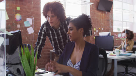 diverse male and female colleagues discussing over computer screen in office