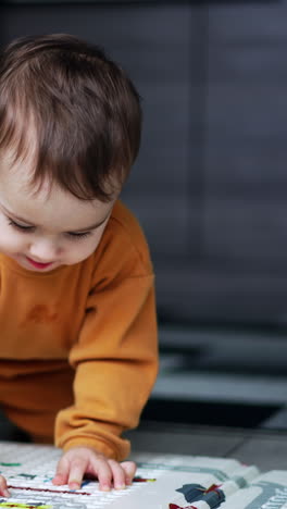 nice little baby boy crawling by the floor and looking carefully at the carpet. toddler playing indoors. blurred backdrop. vertical video