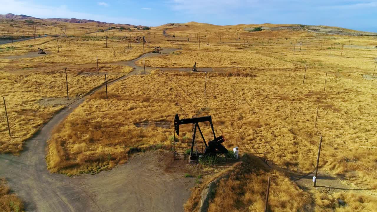 drones de 4k vuelan por plataformas petrolíferas en un campo dorado con cielos azules y nubes