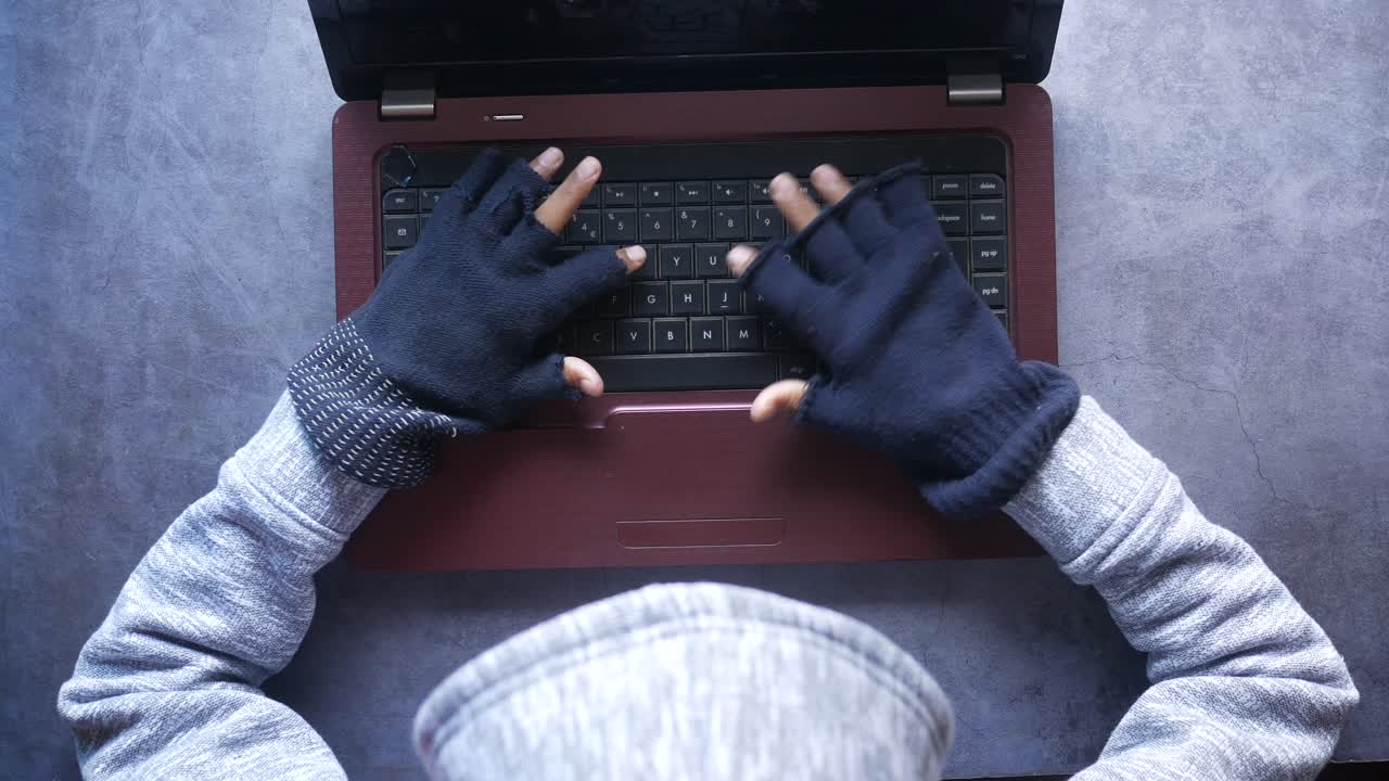 Person Hacking a Laptop with Gloves