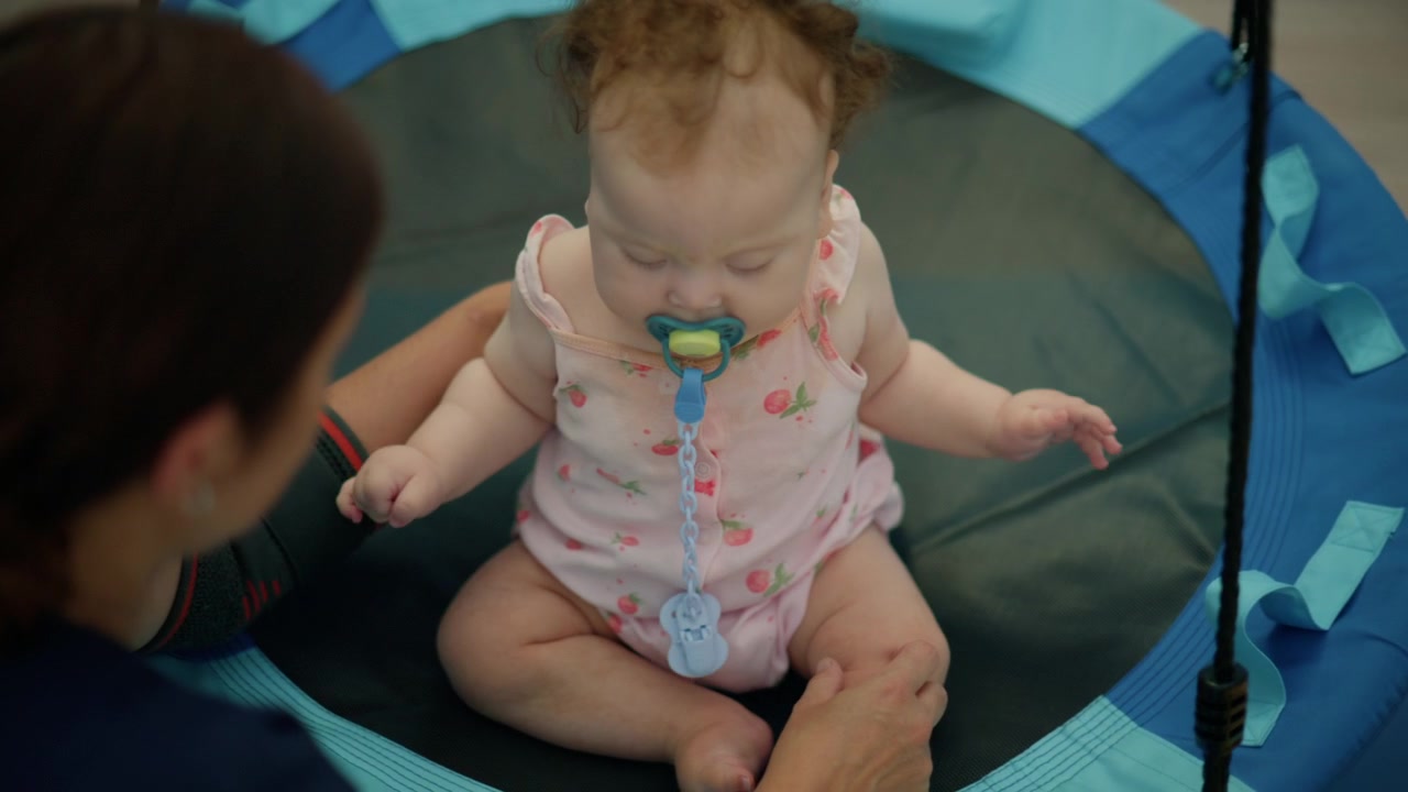 Baby girl with pacifier exploring a colorful toy, held by parents fostering early childhood development and bonding