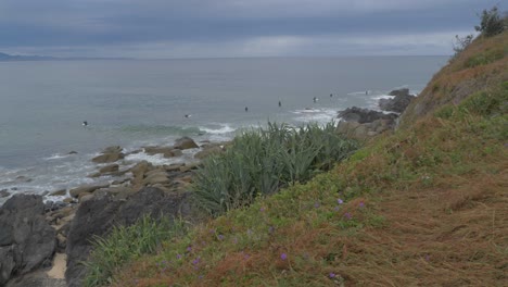 surfers relaxing by the rocky shoreline of lennox point, australia -slow pan