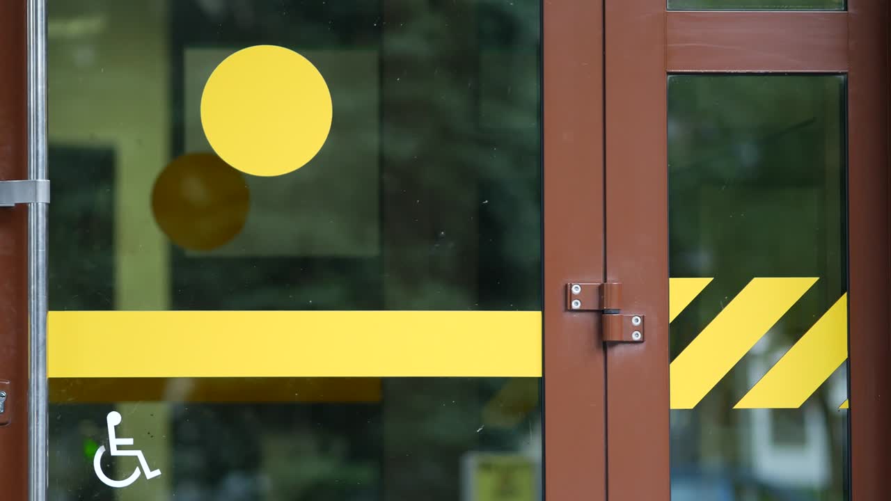 장애인 접근을 표시하는 스티커가 붙은 유리 사무실 문. 노란색 원 입구