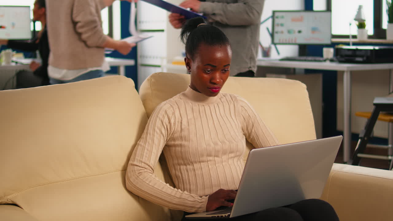 Donna d'affari africana concentrata che risponde alle email digitando sul laptop