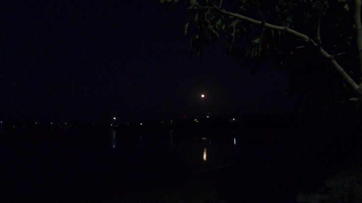 Video 4K di un lago con luna piena e il suo riflesso durante la notte. Sfondo di viaggio per qualsiasi regione costiera o vacanza.