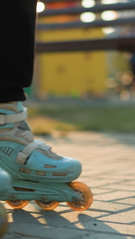 una toma de primer plano de los pies de una persona que usa patines, deslizándose suavemente a lo largo de un camino pavimentado en un parque. el fondo está borroso, centrando la atención en los patines y el movimiento del patinaje