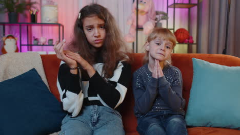 siblings children praying sincerely with folded arms, begging apology, making hopeful wish at home