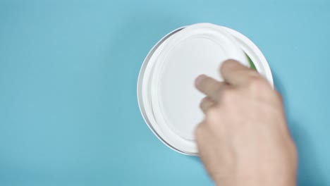 close shot of a hand opening can with green paint