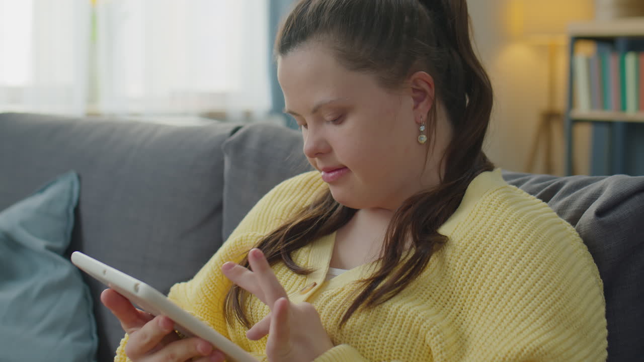 Girl with Down Syndrome Browsing the Web on Tablet at Home