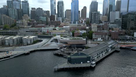 Aerial drone shot of coastal Seattle Aquarium on Elliott Bay waterfront with downtown cityscape - Washington, USA