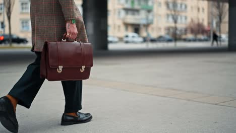 close up young businessman going to work by walk. holding a leather bag in his hand. commuting to the office. public transport