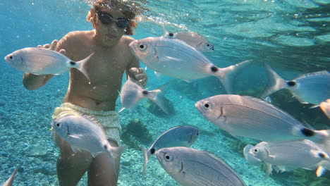 adolescente bajo el agua rodeado de peces