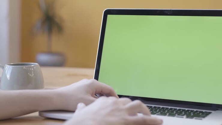Person, die auf einem Laptop mit einem Greenscreen tippt