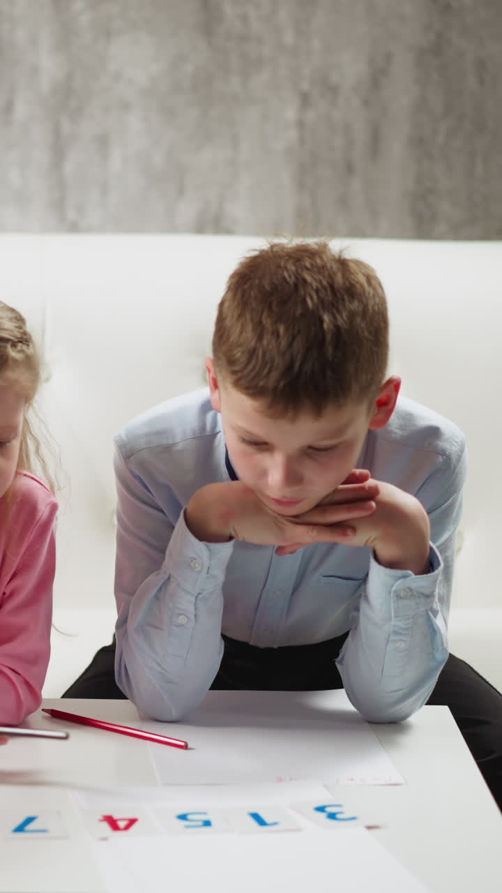 Couple of concentrated children students learns digits with colorful cards doing homework together at coffee table in comfortable living room slow motion