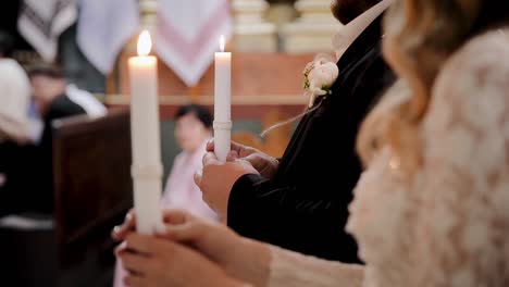 the bride and groom hold lit candles in their hands while standing in the church at the wedding