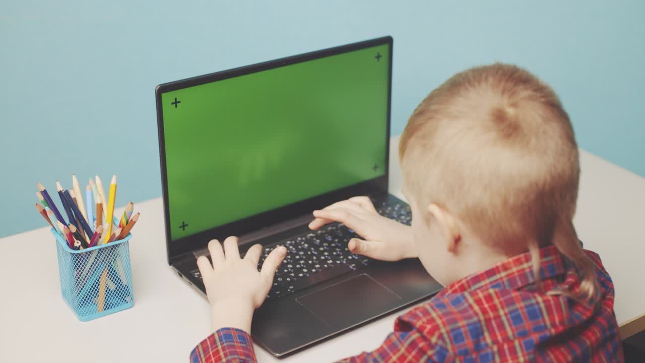 ребёнок работает на ноутбуке с зеленым экраном.