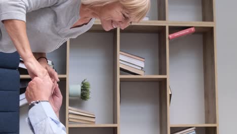 elderly couple's playful interaction by a bookcase