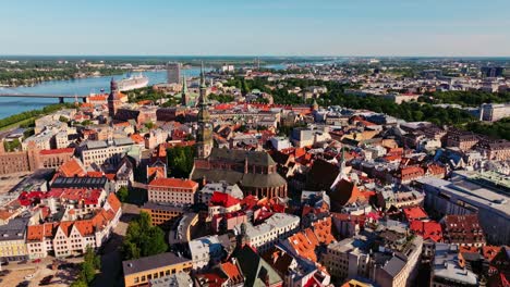 riga old town rooftops glow under bright sun as drone flies backward above city