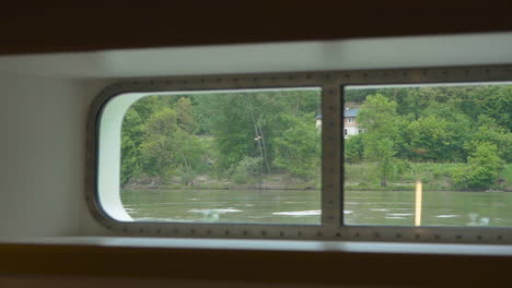 View-Through-Boat's-Window-Cruising-Across-Danube-River-In-Hungary