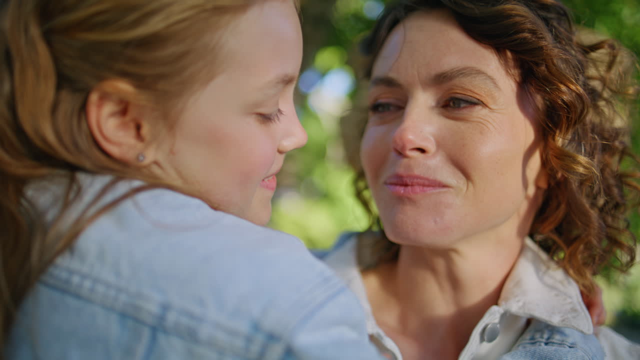 Nahaufnahme einer Mutter, die ihr Kind im sonnigen Park umarmt. Mutter umarmt Tochter