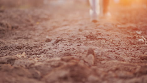 a farmer in boots walks across a plowed field only the legs are visible in the frame