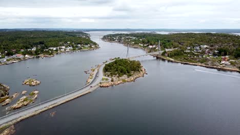 Vista-Aérea-Del-Puente-Puttesund-En-Noruega,-Que-Abarca-Un-Tranquilo-Canal-Rodeado-De-Exuberantes-Paisajes-Verdes-Y-Pintorescas-Casas-Costeras.