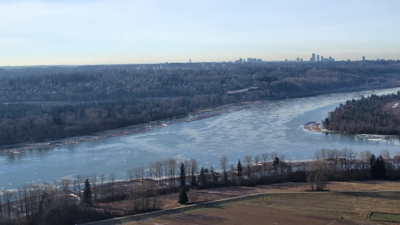 vista aérea de un río helado con un horizonte de la ciudad en el horizonte soleado
