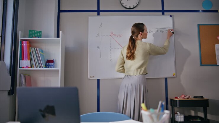 Insegnante in gamba che spiega matematica usando la lavagna in un'aula scolastica.