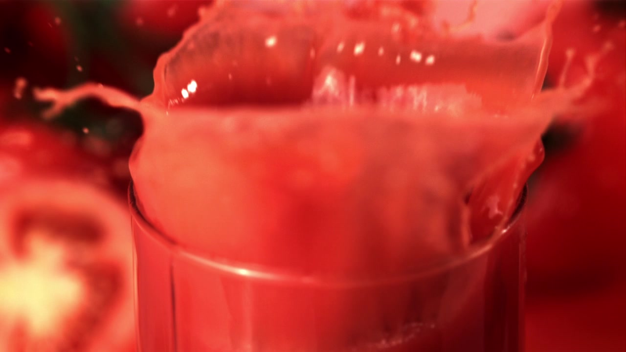Movimento rallentato di pomodoro a fette che schizza nel succo di pomodoro rosso