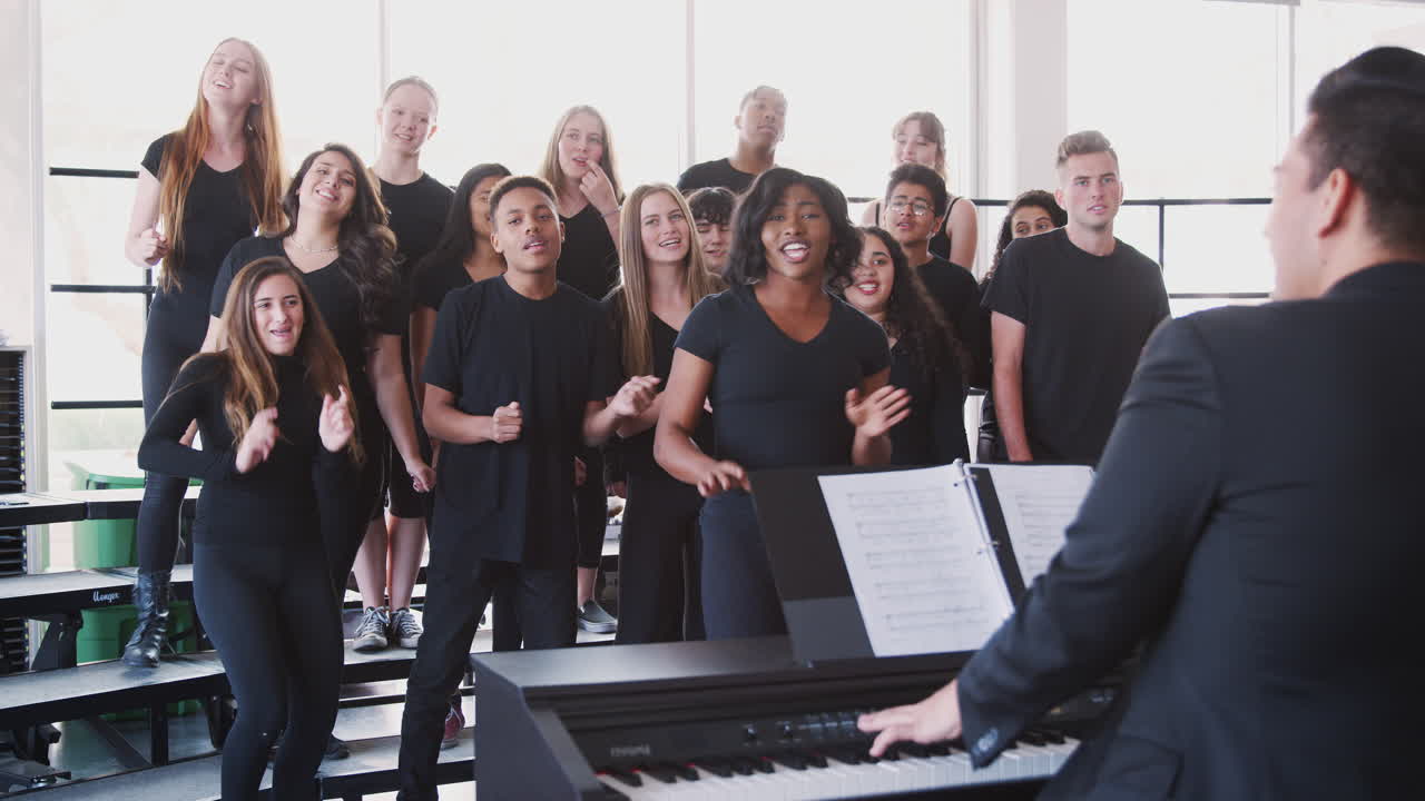 estudiantes masculinos y femeninos cantando en el coro con el maestro en la escuela de artes escénicas
