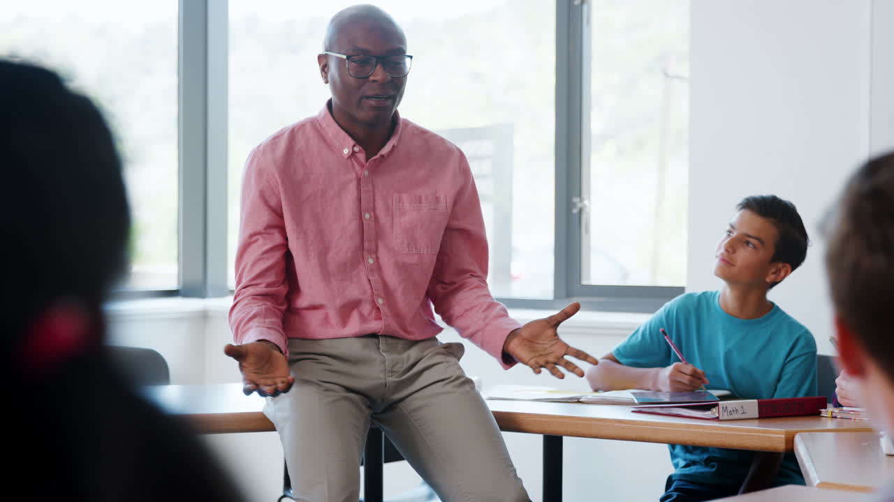 High School Tutor Sitting On Desk And Teaching Class Shot In Slow Motion