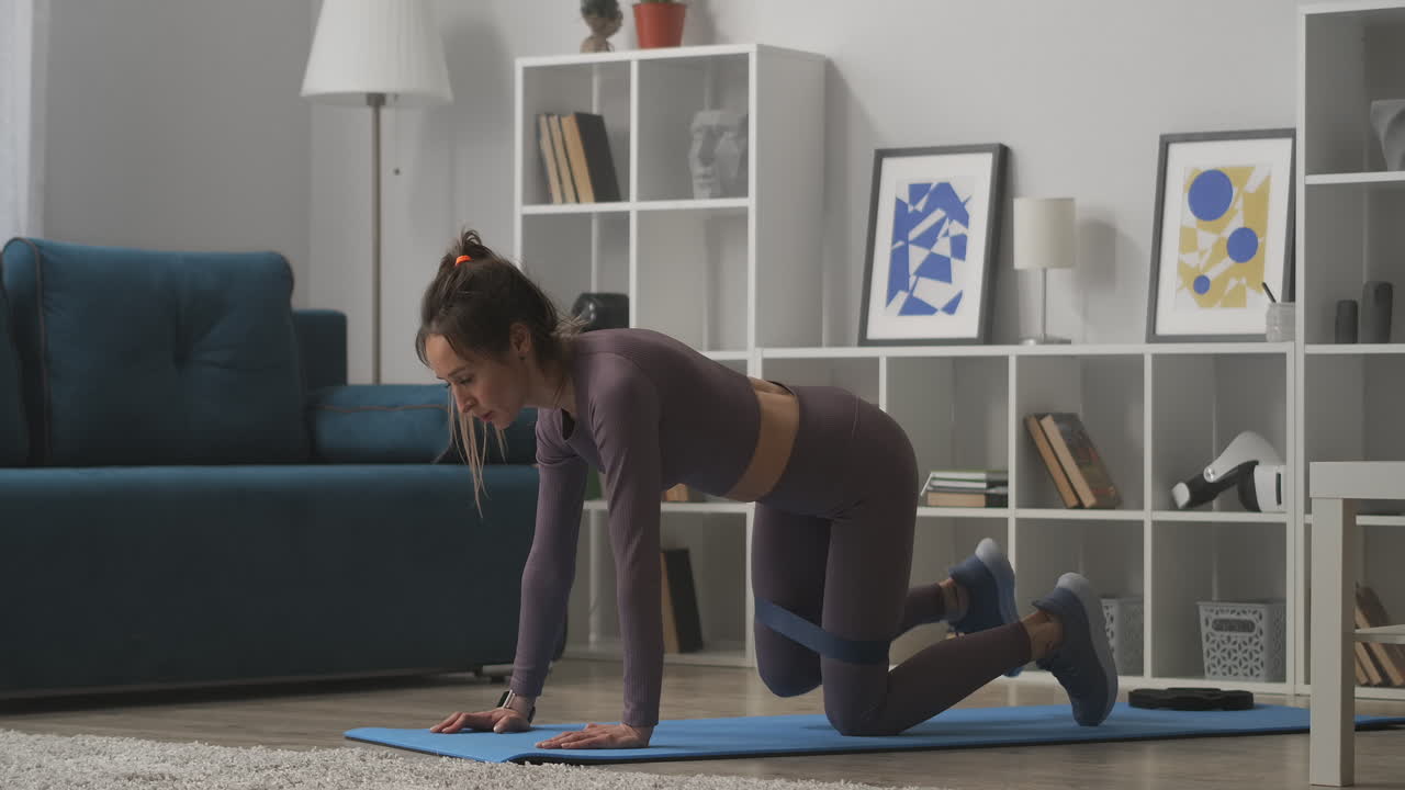 fitness en el hogar de la mujer joven deportiva ejercicios con banda elástica para las piernas ejercicios musculares en la sala de estar estilo de vida saludable y práctica de bienestar
