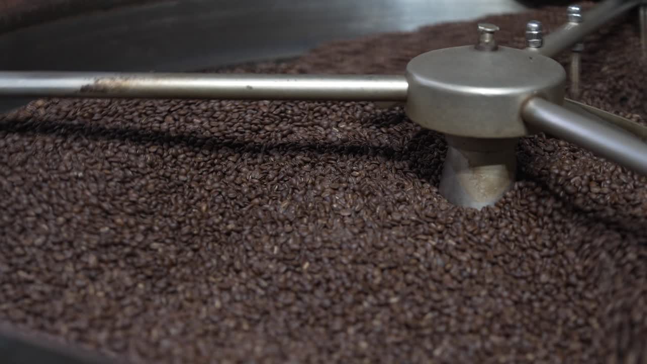 A rotating arm agitates roasted coffee beans inside the cooling drum