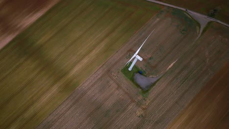 Wide-shot-of-a-white-wind-turbine-contrasting-with-the-dark-ground