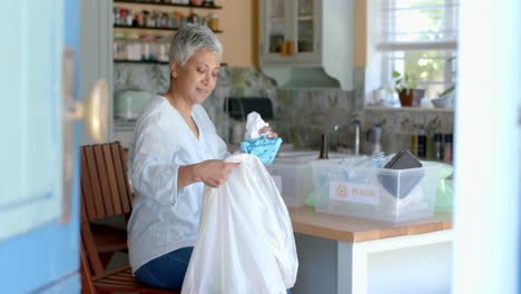 happy senior biracial woman segregating waste at home, slow motion