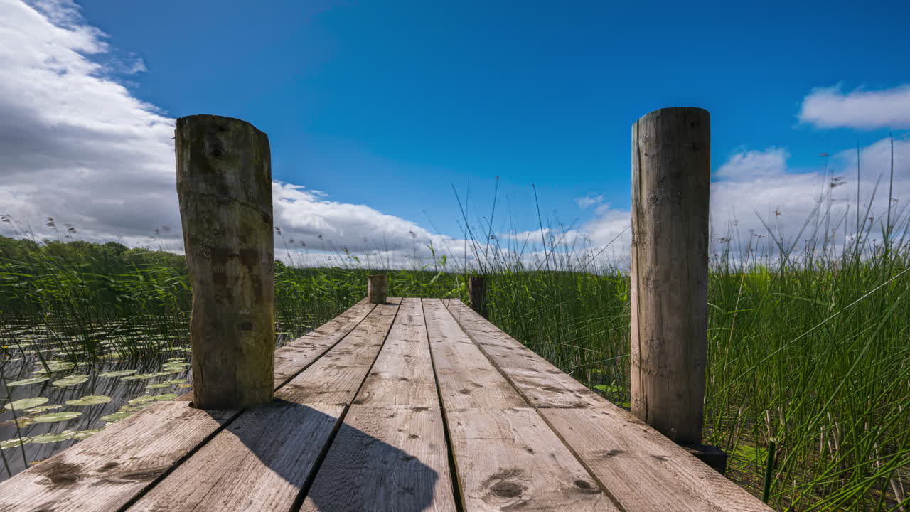 timelapse del embarcadero de madera local rodeado de juncos en lough key en el condado de roscommon en irlanda en un día soleado con nubes pasajeras en el cielo durante la primavera