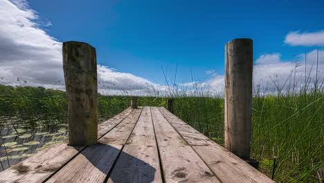 timelapse of local timber jetty surrounded by reeds at lough key in county roscommon in ireland on sunny day with passing clouds in the sky during spring