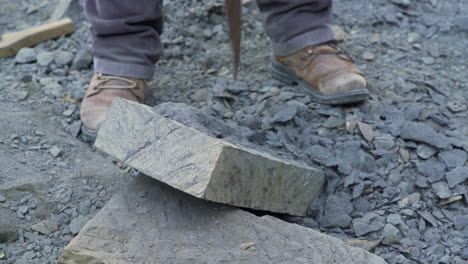 handheld shot showing a stone craftsman using a pick on a slab of cancagua, in the city if ancudon chiloe island