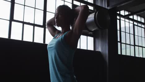 African-american-woman-resting-breathing-heaviily-after-exercising-in-an-empty-urban-building