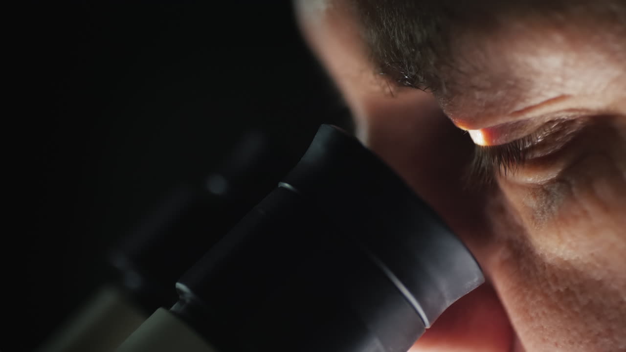 실험실에서 현미경으로 작업하는 과학자의 측면